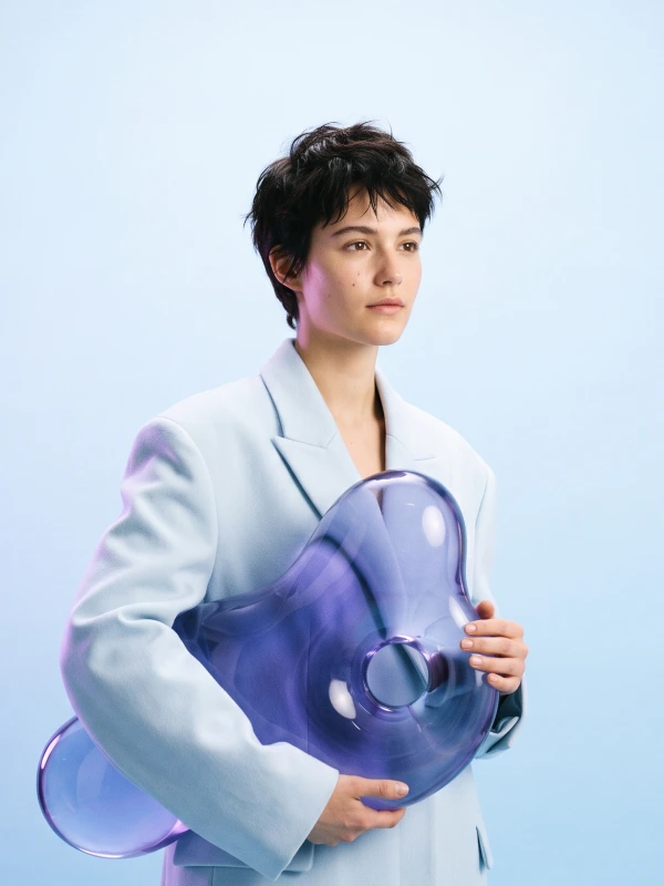 Portrait in a sky-blue studio with a glass Runblob shape